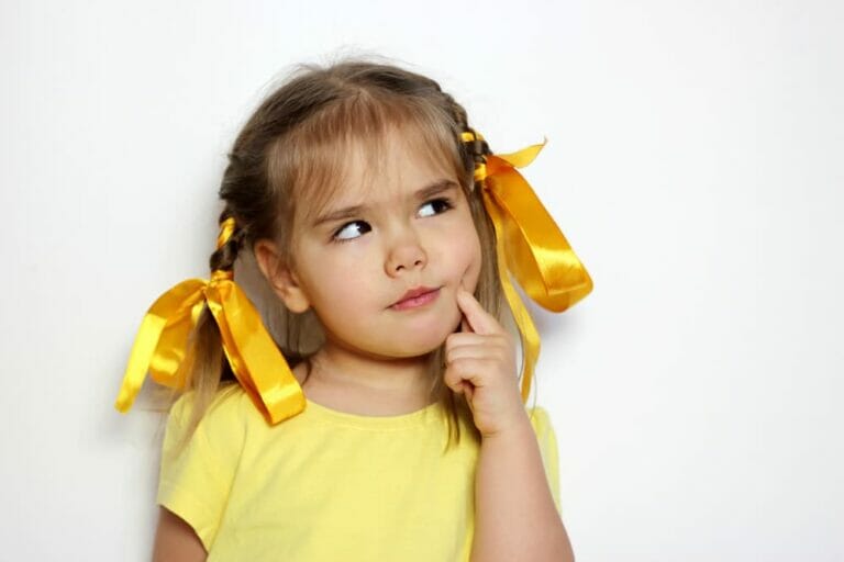 A young girl with pigtails and yellow ribbons looking thoughtful with her finger on her cheek