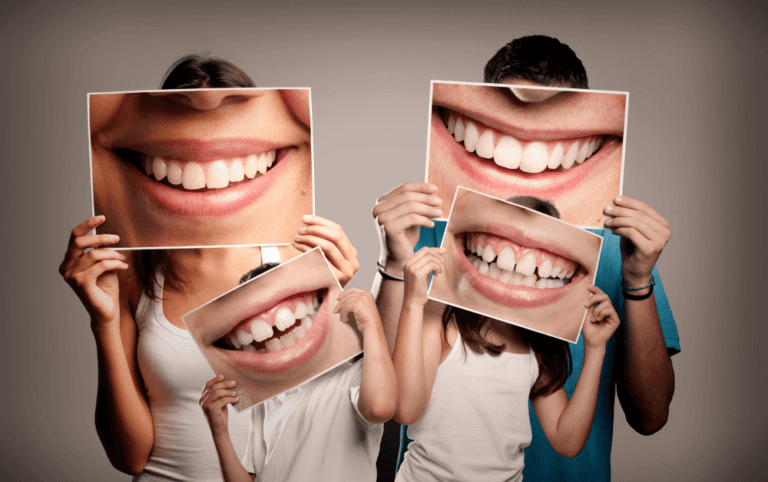 Two adults and two children holding photos of large smiling mouths in front of their faces