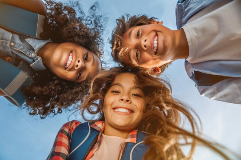 Three children looking down into the camera and smiling